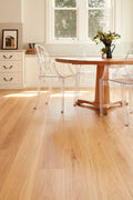 Dining room with wooden table and clear chairs on a light wood floor.