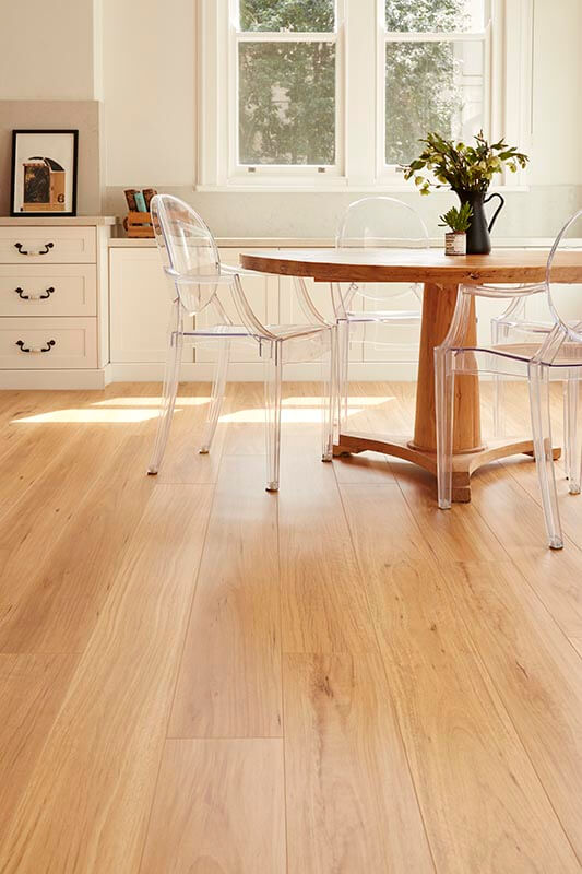 Dining room with wooden table and clear chairs on a light wood floor.