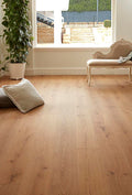 Wooden floor with a view of a garden through a window, featuring a sofa and plant.