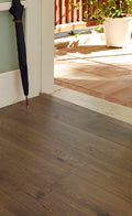Wooden floor with a partially open umbrella and a potted plant in the background.