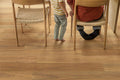 Two people sitting on chairs with a focus on wooden flooring.