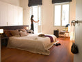 Modern bedroom with a bed, wardrobe, and a person standing by a window.