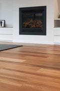 Wooden floor with a fireplace in a room with white walls and a rug.