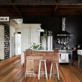 Modern kitchen with wooden island, stools, and various appliances.