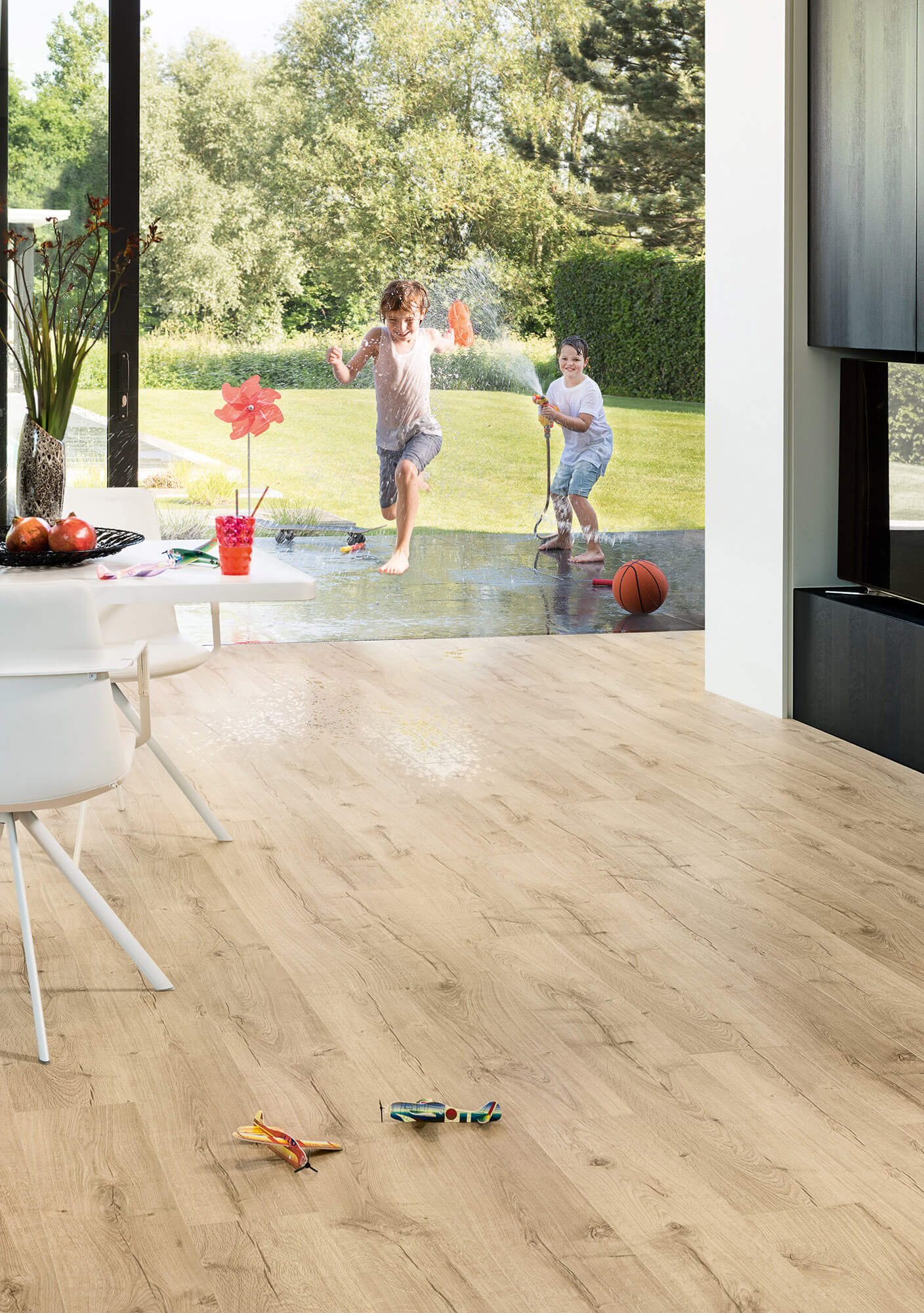Children playing with toys on a wooden floor in a modern living room.