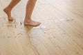 Person walking on a wet wooden floor with water damage.