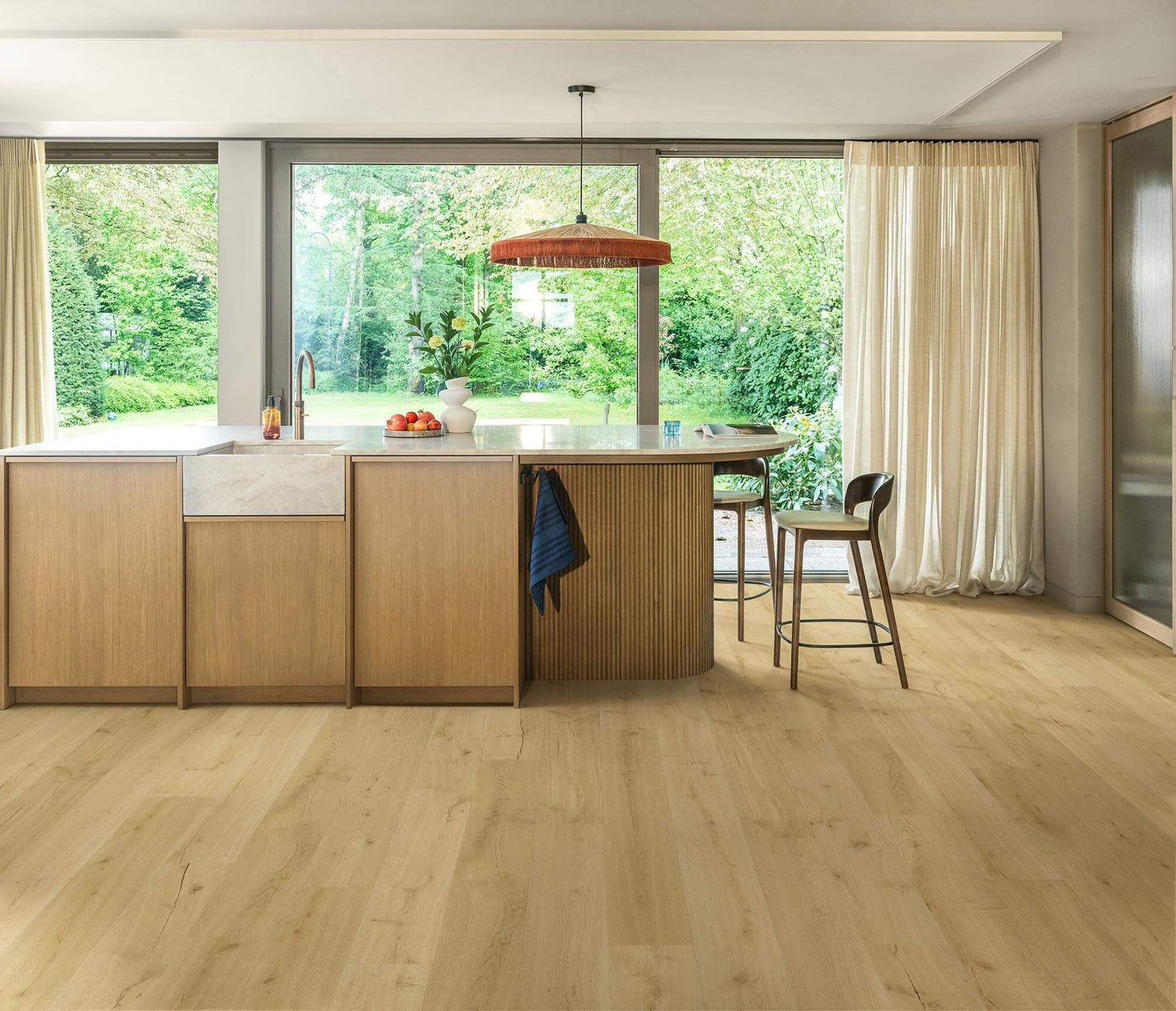 Modern kitchen with wooden cabinets, island, and stools near large windows.