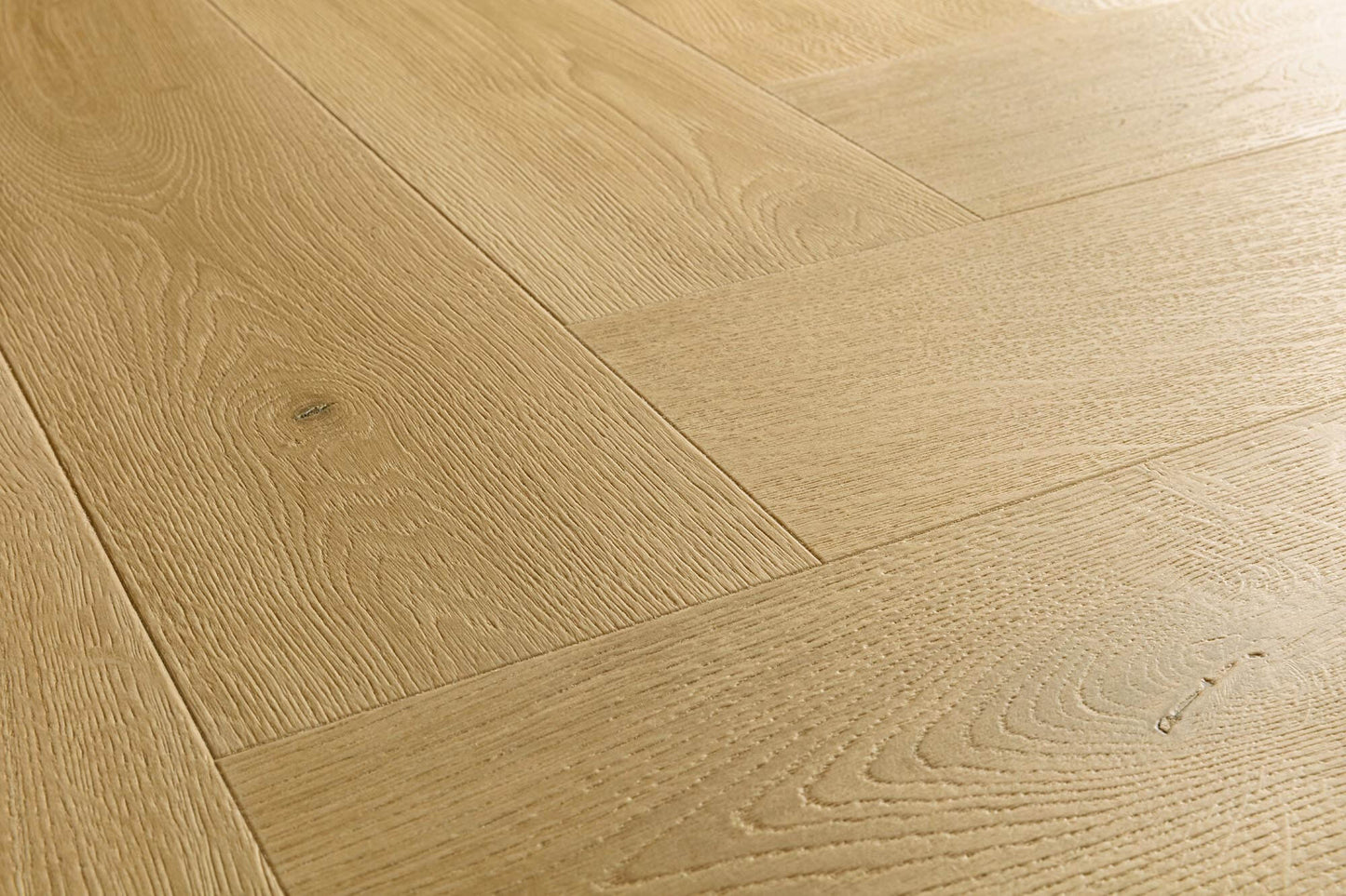 Light oak wood flooring planks arranged in a herringbone pattern, showing natural wood grain and subtle knots.