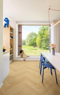 Modern interior with a large window view of greenery, a child sitting on the windowsill, and a desk with chairs.
