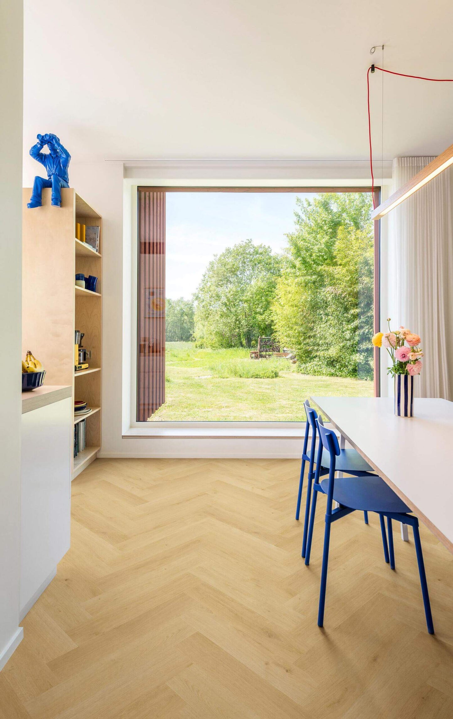 Modern interior with a large window, blue chairs, and a white table.