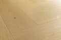 Light oak wood flooring planks arranged in a herringbone pattern, showing natural wood grain and a subtle knot.