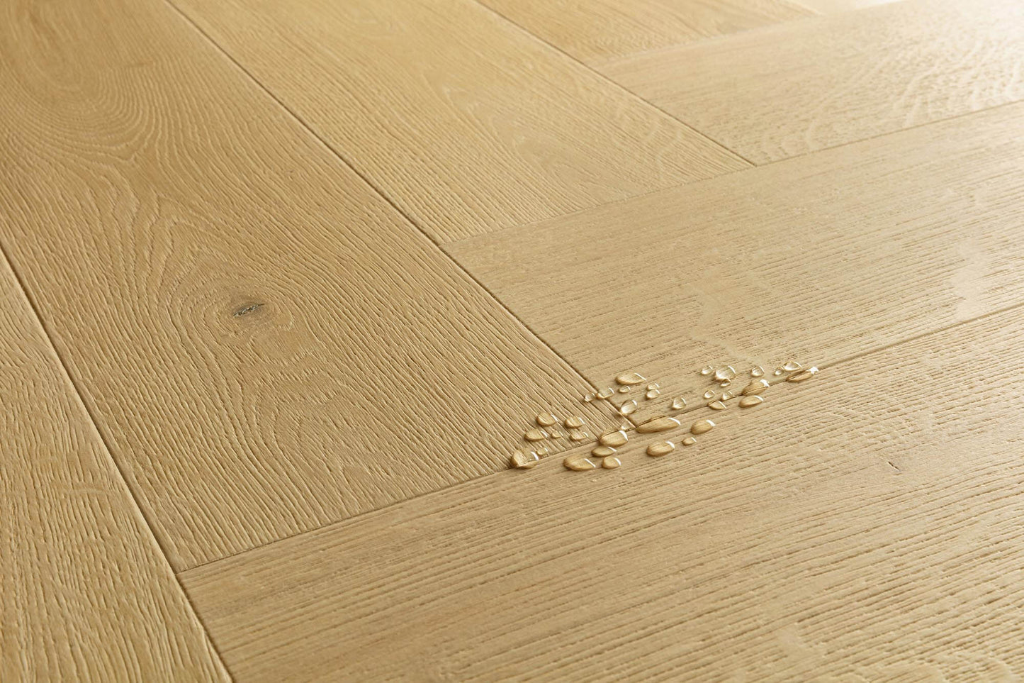 Light oak wood flooring planks arranged in a herringbone pattern, with a small cluster of broken glass chips on the surface.