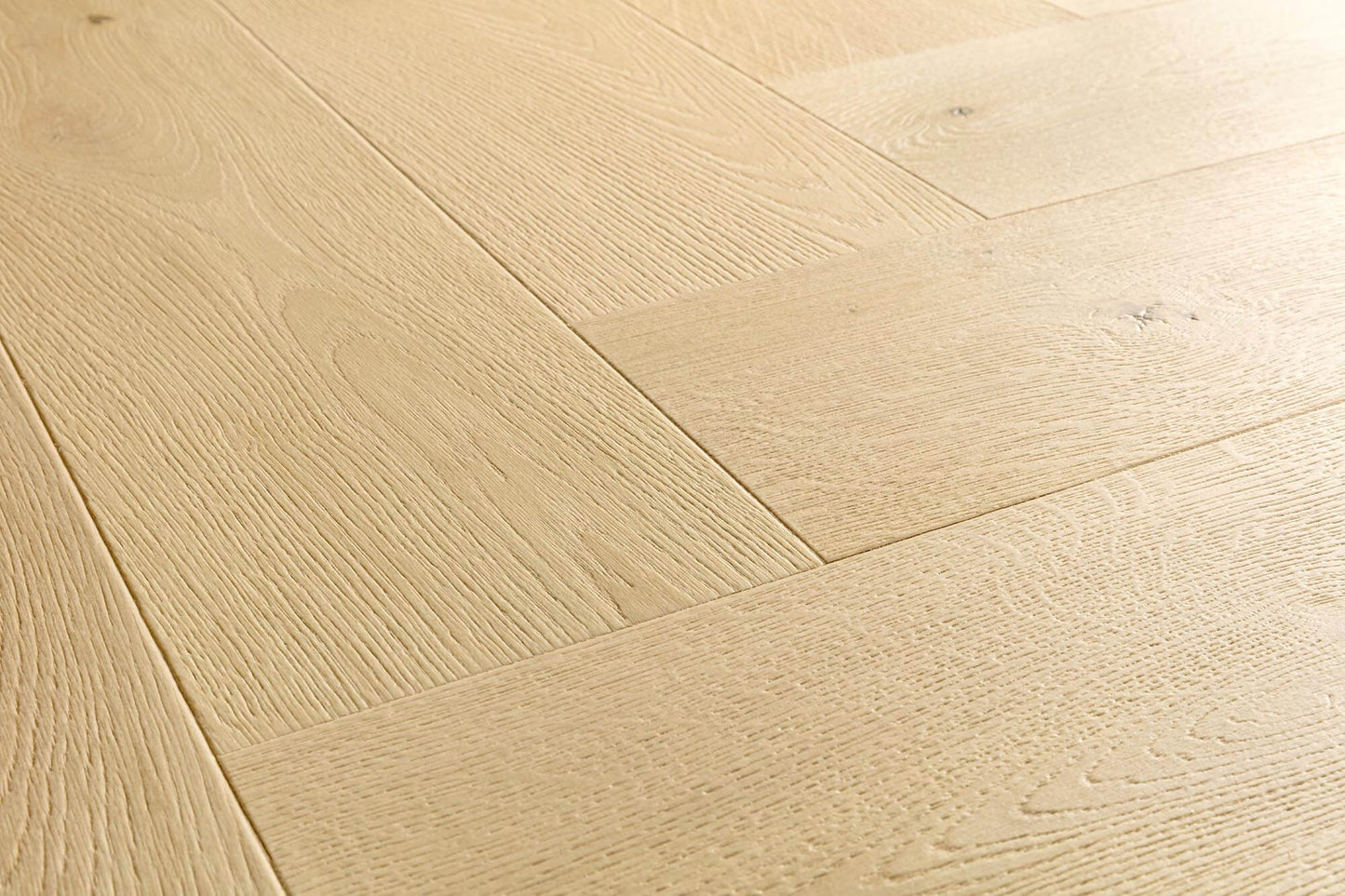 Light natural oak wood flooring planks arranged in a herringbone pattern, showing detailed wood grain and subtle knots.
