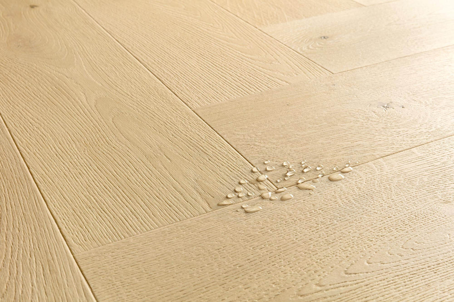 Light natural oak wood flooring planks arranged in a herringbone pattern, with a small cluster of scattered wood shavings on the surface.