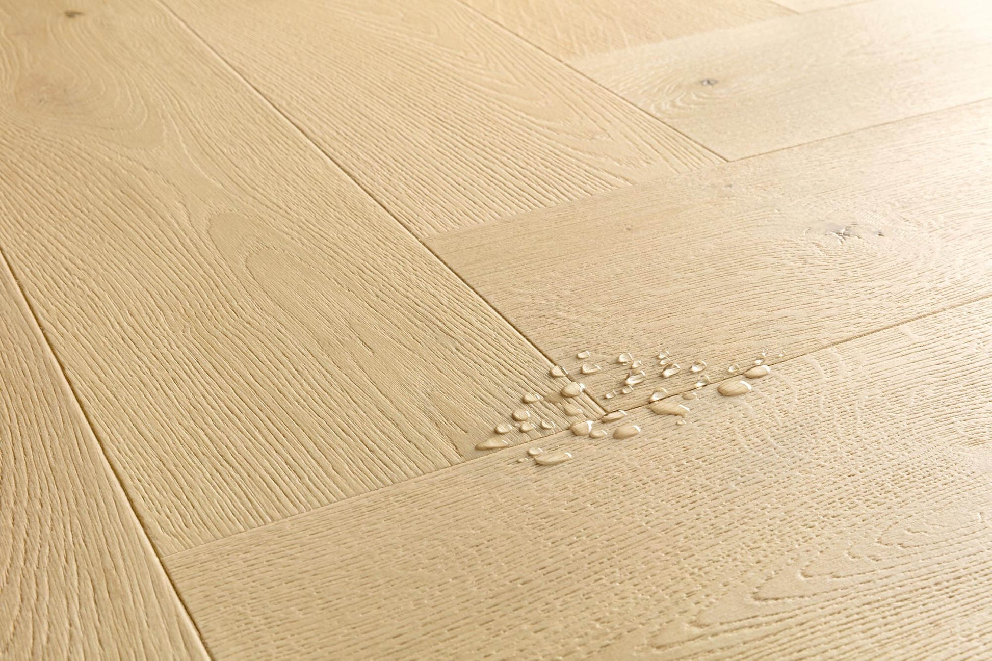 Light natural oak wood flooring planks arranged in a herringbone pattern, with a small cluster of scattered wood shavings on the surface.