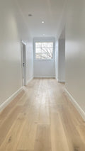 Long hallway with wooden flooring and a window at the end