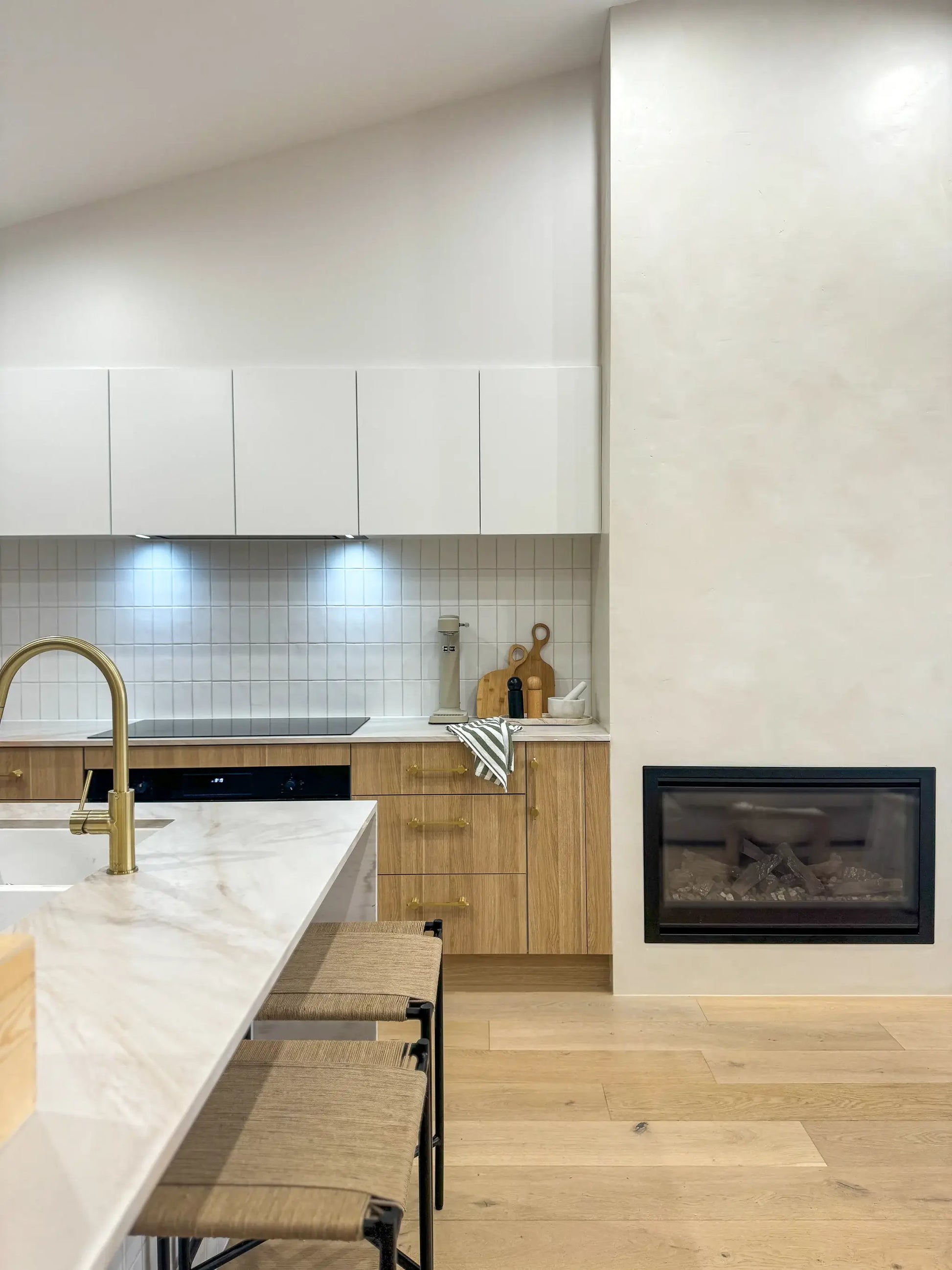 Modern kitchen with white cabinets, marble countertop, and wooden floor.