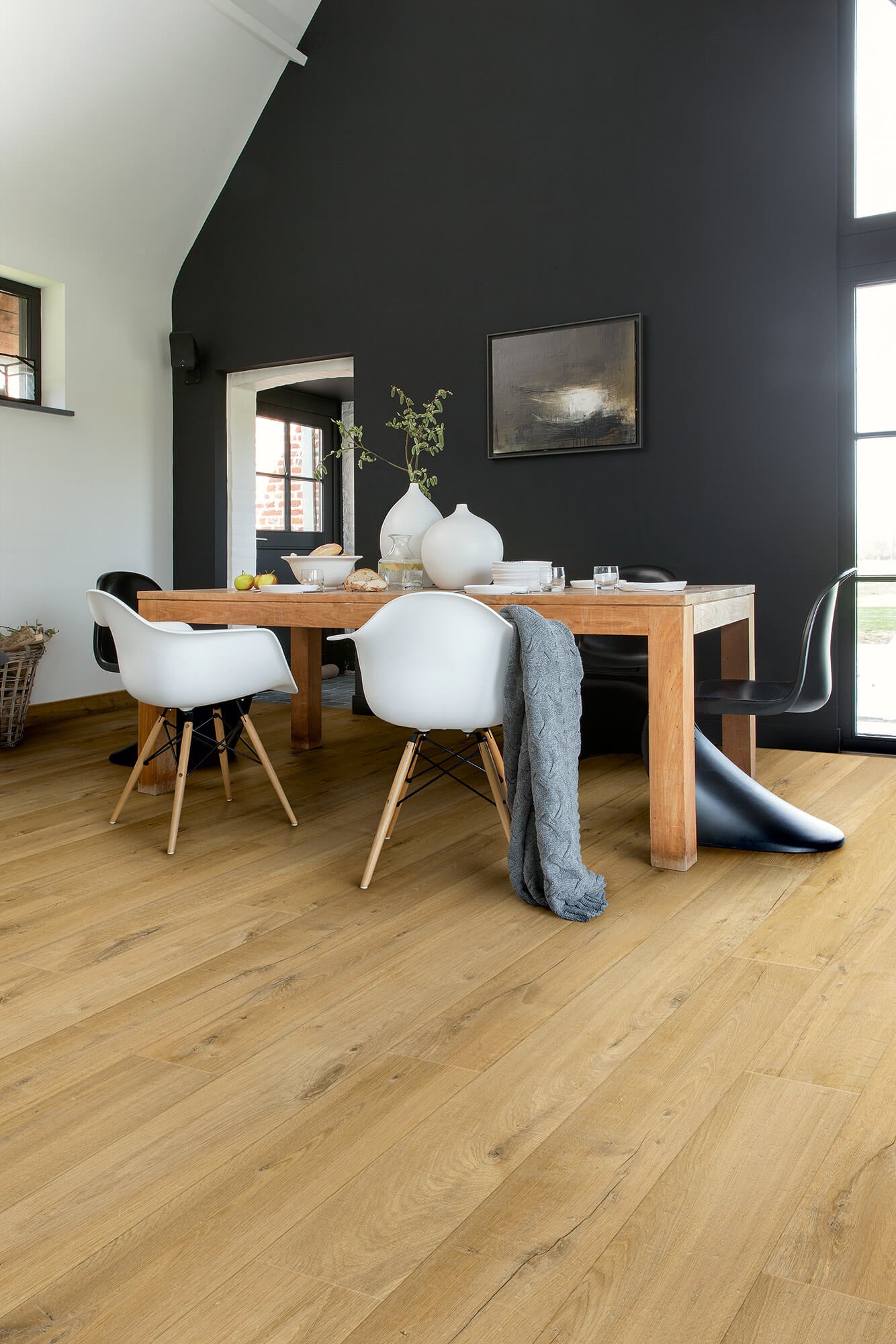 Dining area with wooden table, white chairs, and a dark wall.