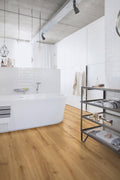 Modern bathroom with white bathtub, wooden floor, and shelves.