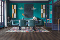 Modern dining room with teal walls, colorful rug, and stylish furniture.