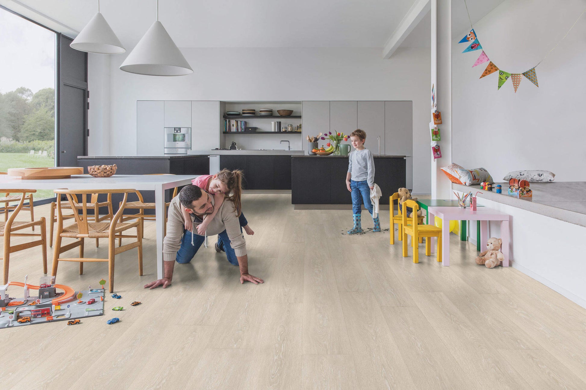 Family playing on a wooden floor in a modern kitchen