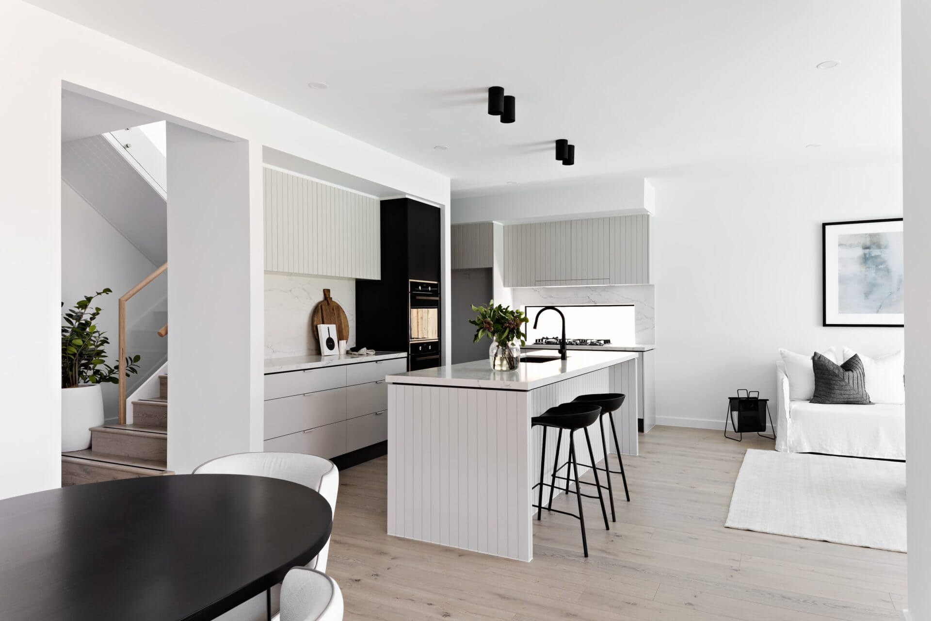 Modern kitchen and living room with white walls and black fixtures