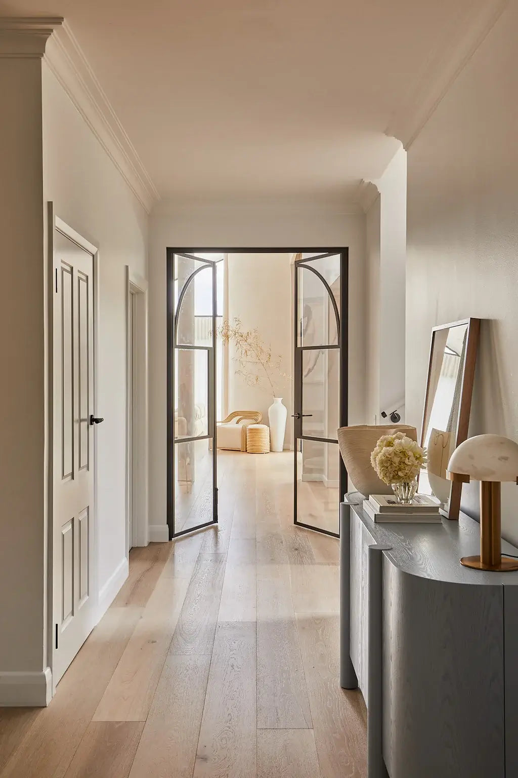 Modern interior hallway with a mirror, lamp, and decorative items.