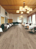 Large room with wooden flooring, tables, chairs, and chandeliers.