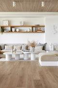 Modern living room with wooden floor, white walls, and neutral color furniture.