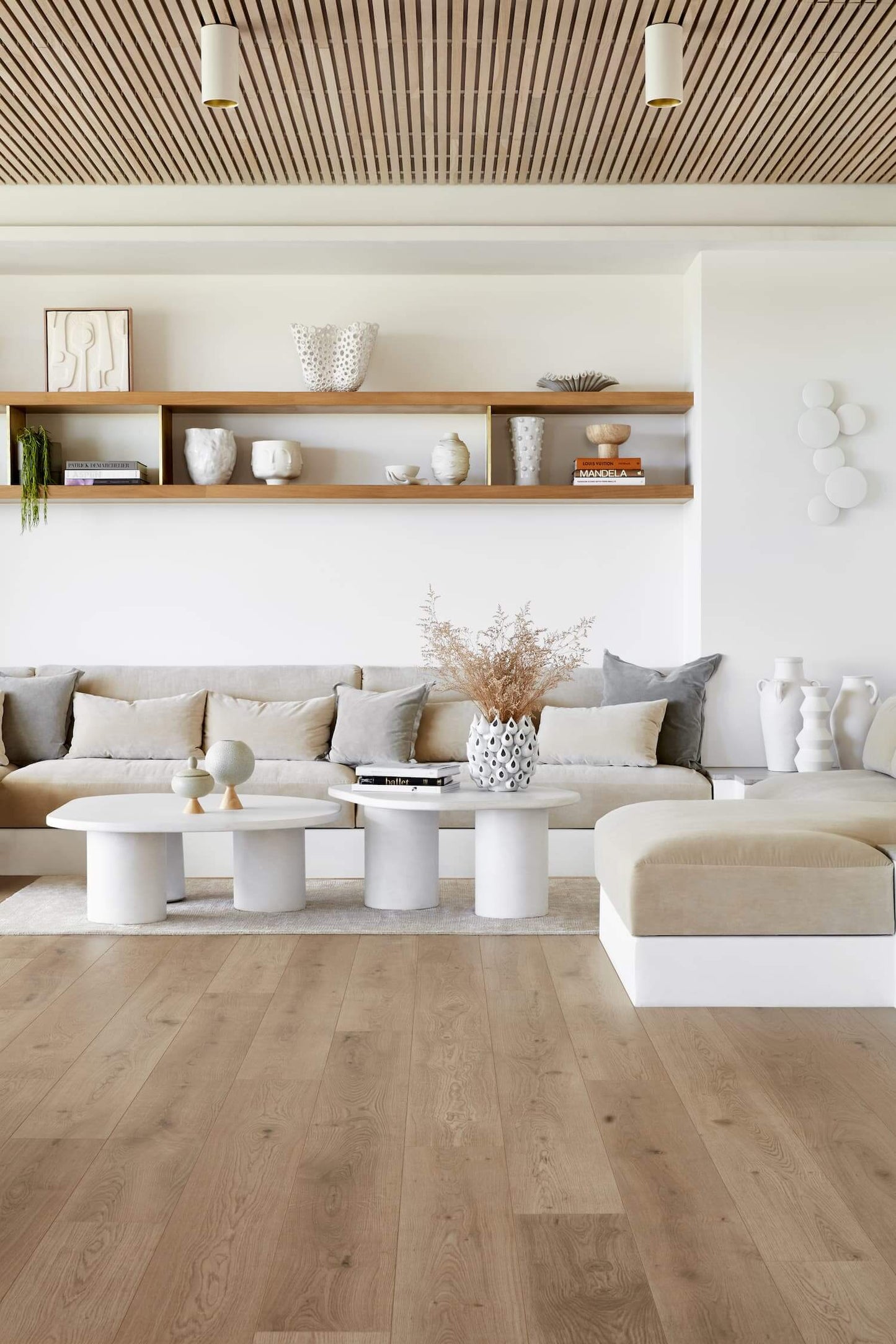 Modern living room with wooden floor, white walls, and neutral color furniture.