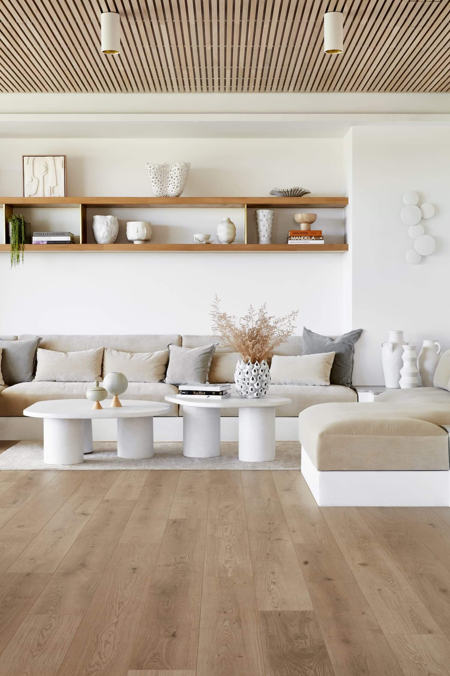 Modern living room with wooden floor, white walls, and neutral color furniture.