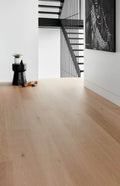 Modern interior with wooden floor, black staircase, and artwork on white wall.