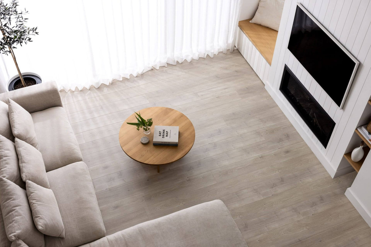 Modern living room with a beige sofa, wooden coffee table, and TV unit.