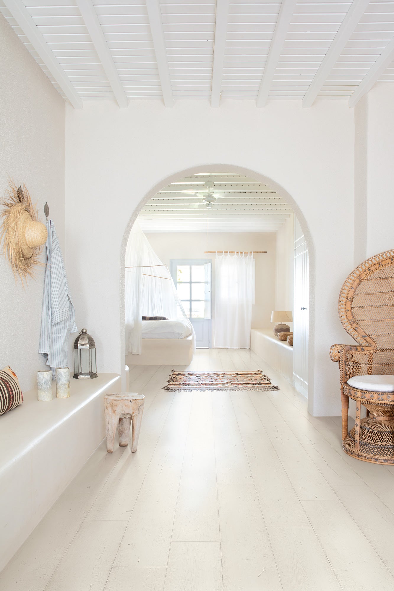 Bathroom with white walls, wooden floor, and wicker chair.