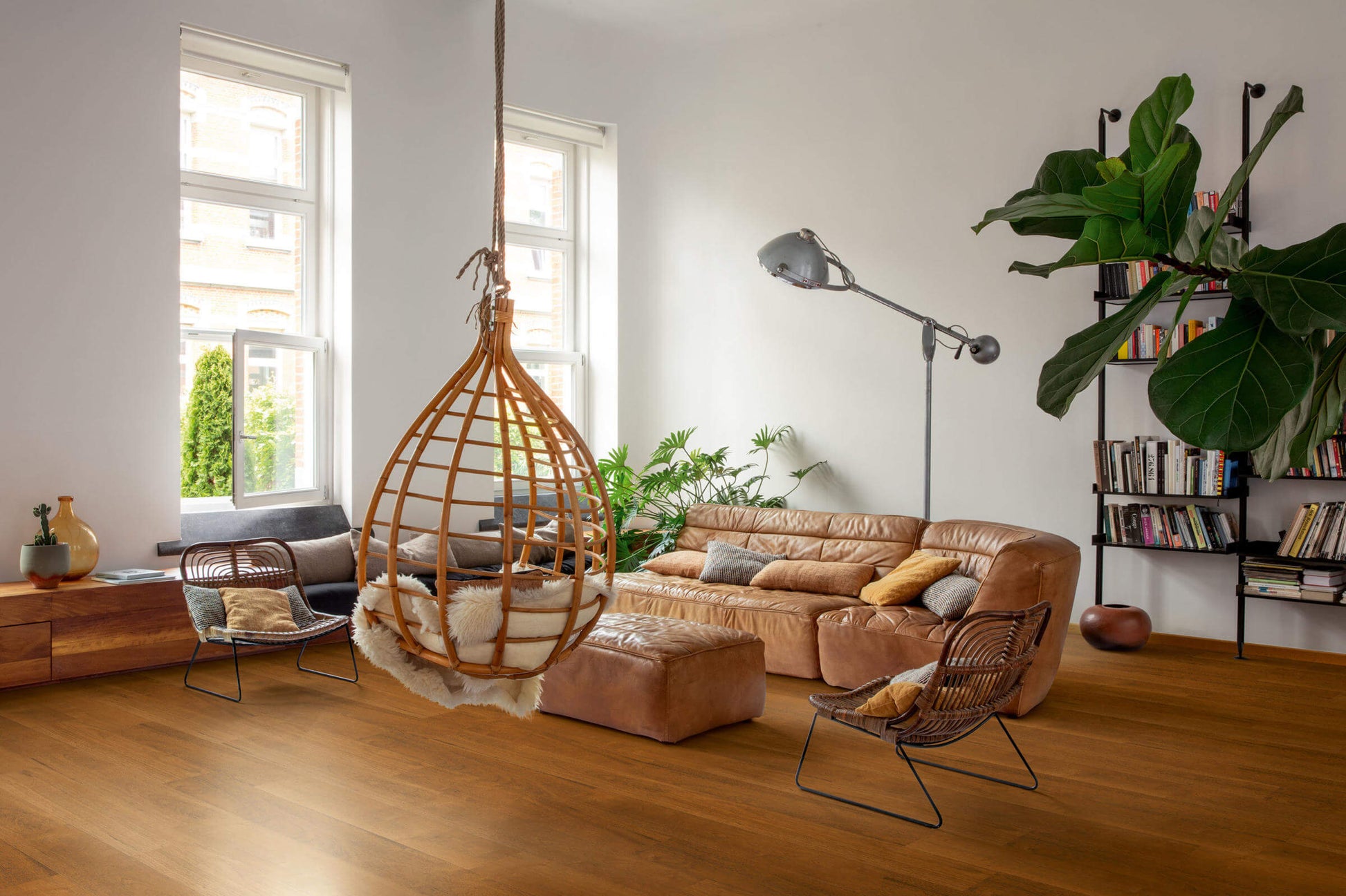 Modern living room with a hanging chair, sofa, and bookshelf.