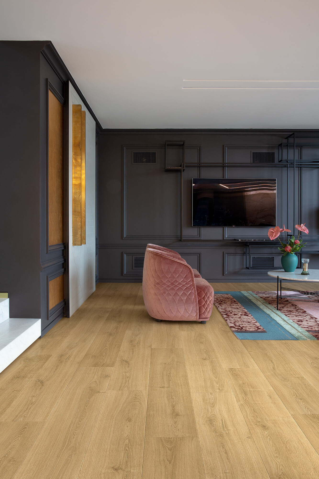 Modern living room with wooden flooring, pink armchair, and television.