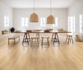 Dining area with a long wooden table and stools in a bright room.