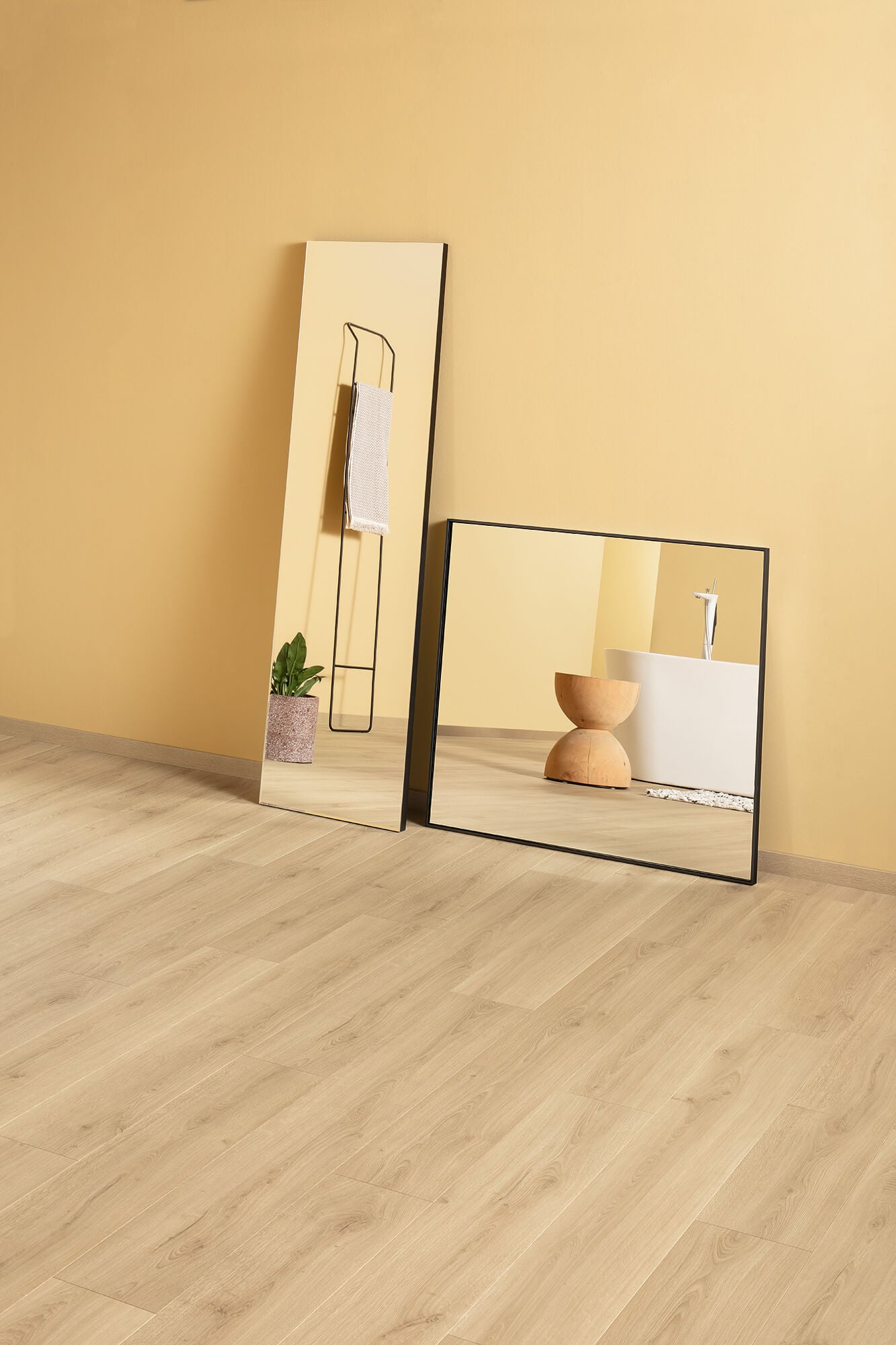 Two mirrors on a wooden floor with a beige wall background