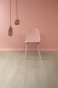Pink chair against a pink wall with two hanging lamps.