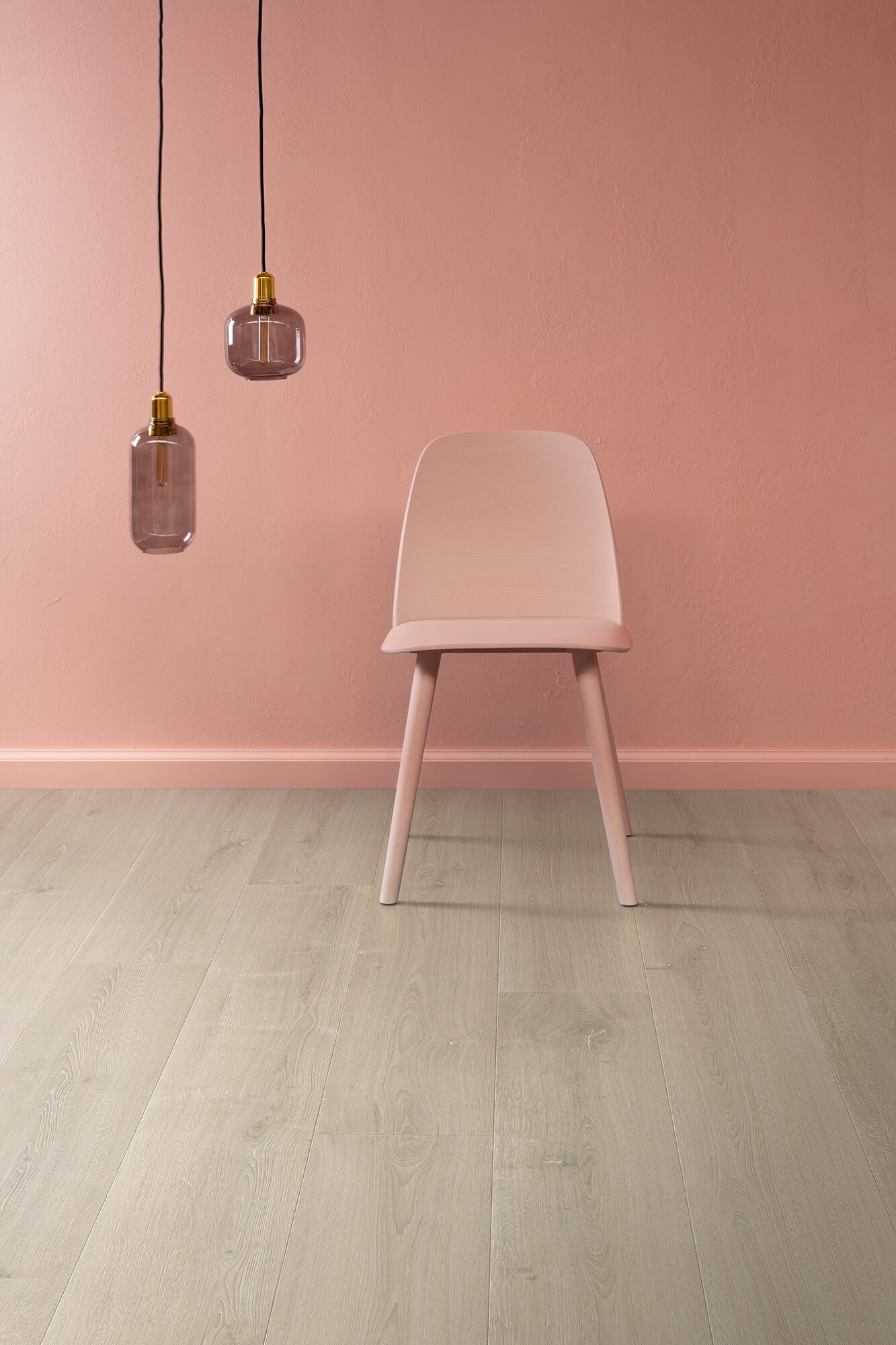 Pink chair against a pink wall with two hanging lamps.