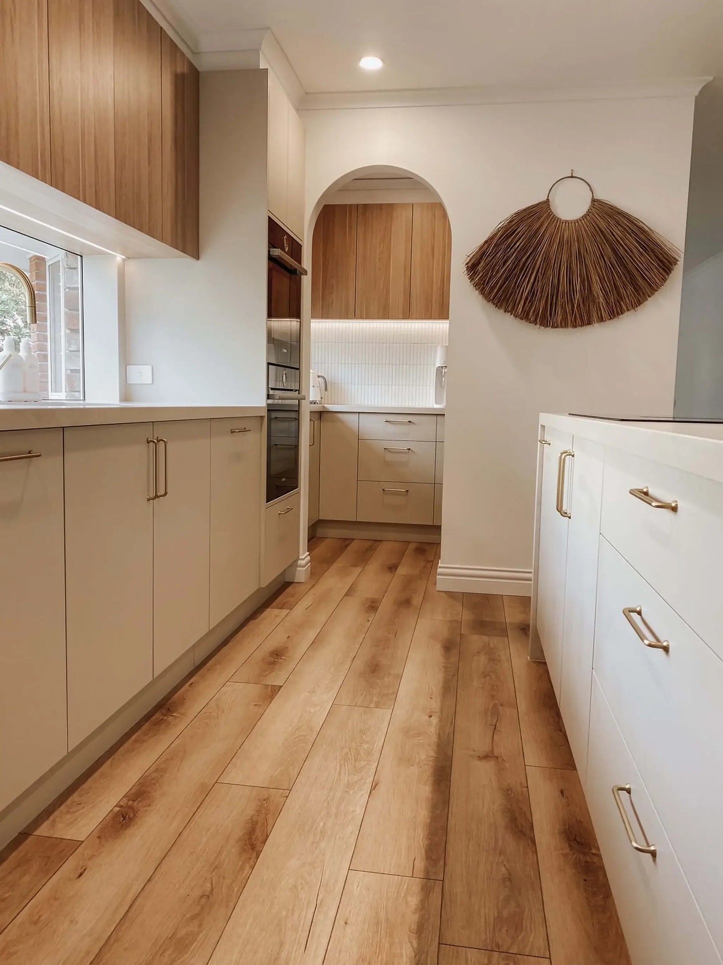 Modern kitchen with wooden flooring and light-colored cabinets.