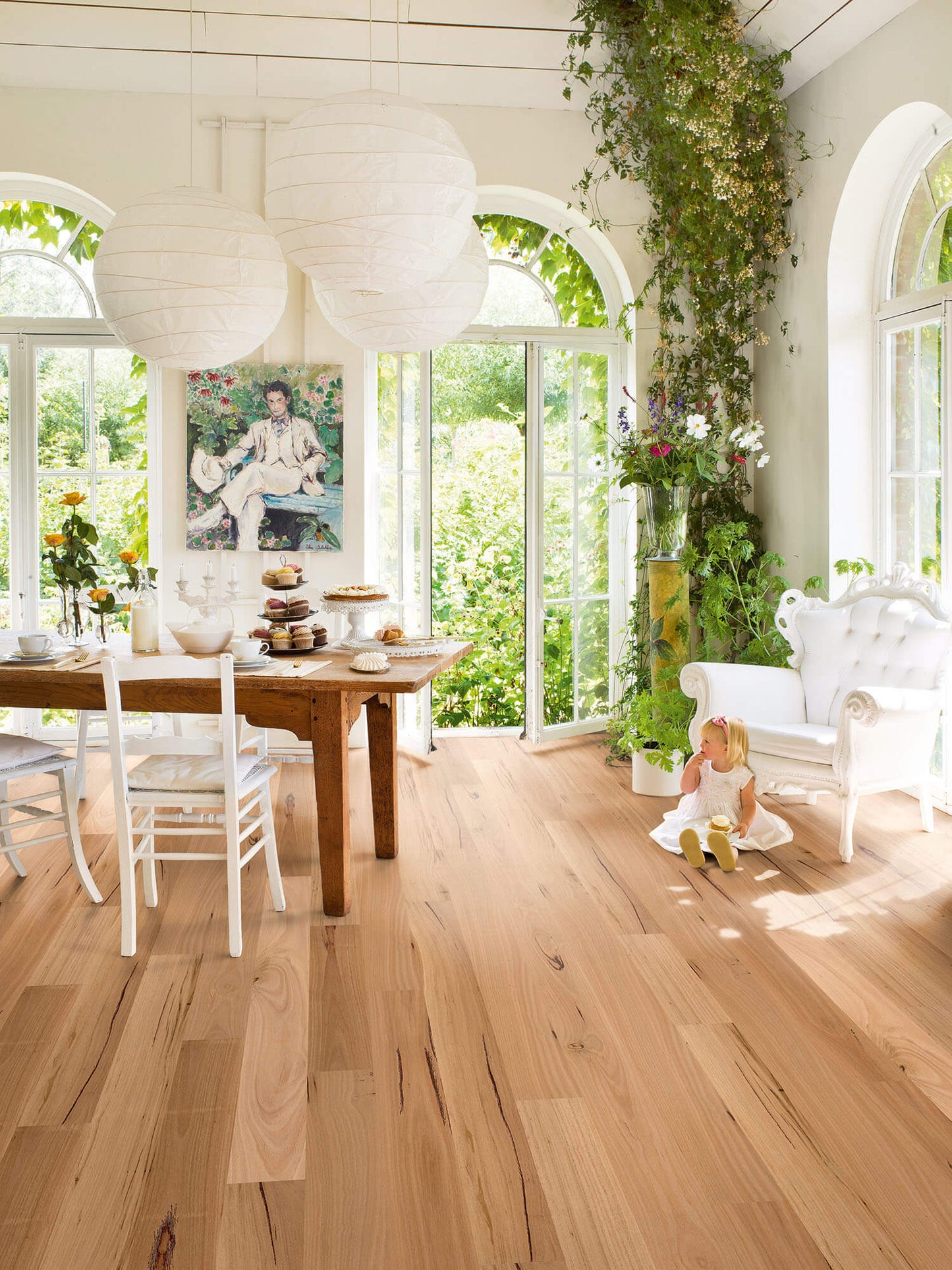 Brightly lit room with wooden floor, dining table, and large windows.