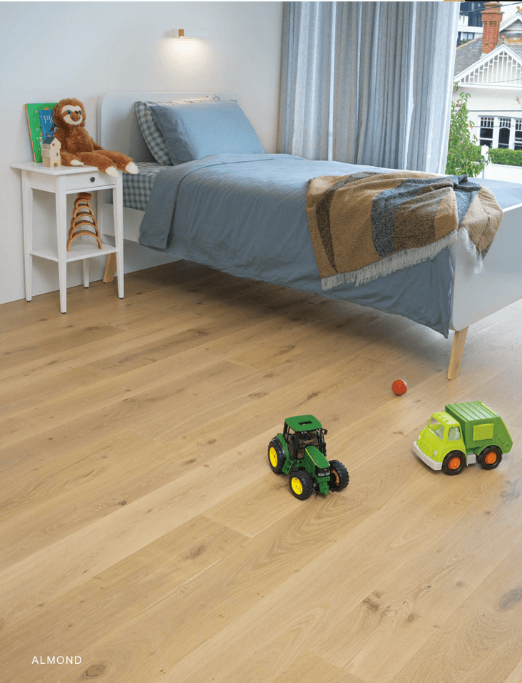 Children's bedroom with toys on a wooden floor, featuring a bed and nightstand.