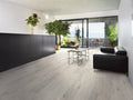Modern living room with black sofa, glass coffee table, and large windows.