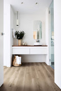Modern bathroom with wooden vanity, mirror, and plant.