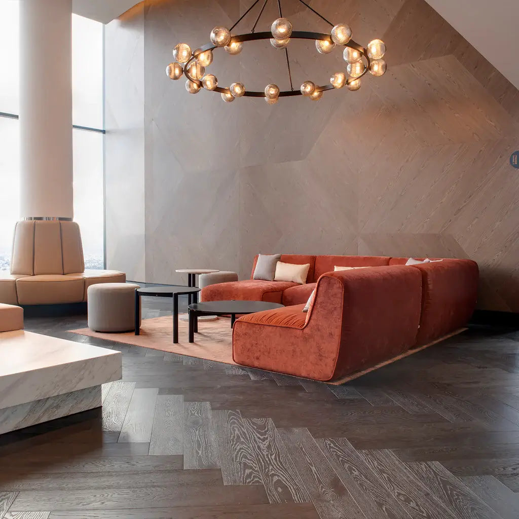 Modern living room with a red sofa, chandelier, and wooden floor.