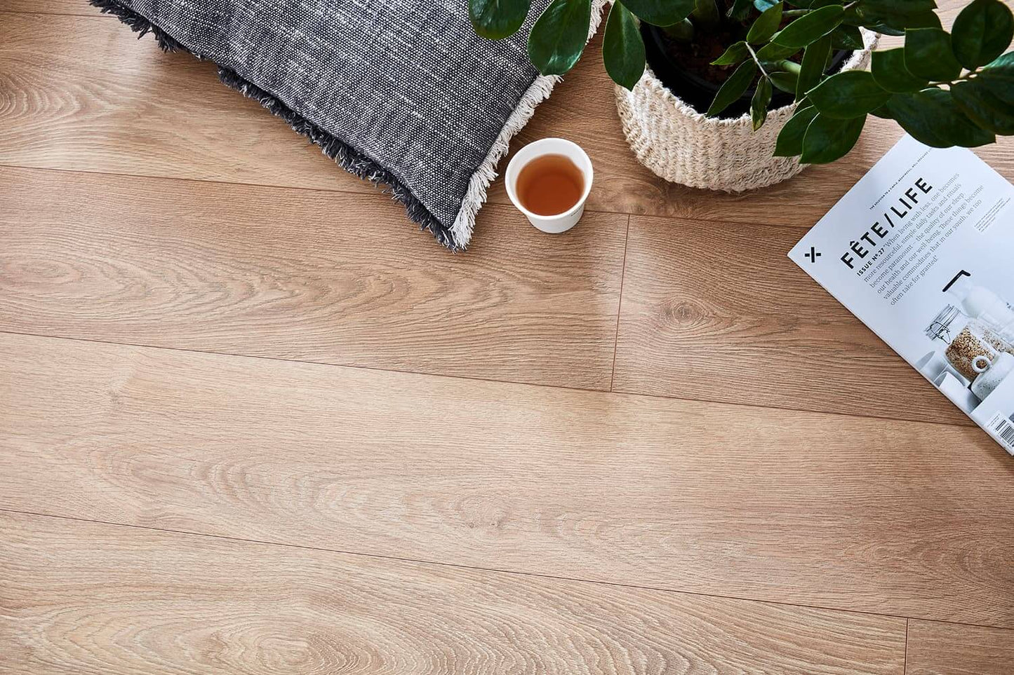 Wooden floor with a plant, cup of tea, and magazine.
