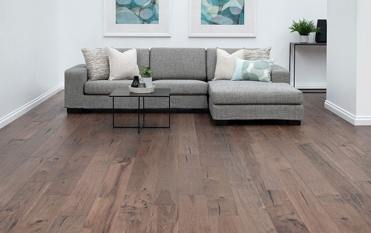 Living room with a gray sectional sofa, coffee table, and framed artwork on a wooden floor.