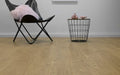Black chair with pink cushion and wire basket on wooden floor against white wall
