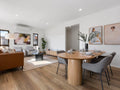 Modern living room with a dining table and chairs, featuring neutral colors and minimal decor.